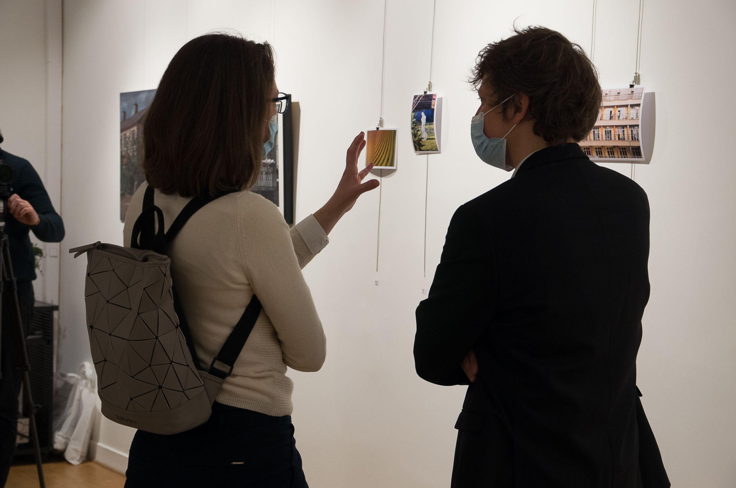 izložba u parizu, vide se dve osobe sa leđa koje razgovaraju dok gledaju u fotografije