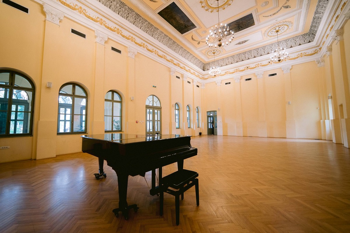 eđšeg slika unutrašnjosti salona u čijem se centru nalazi klavir
